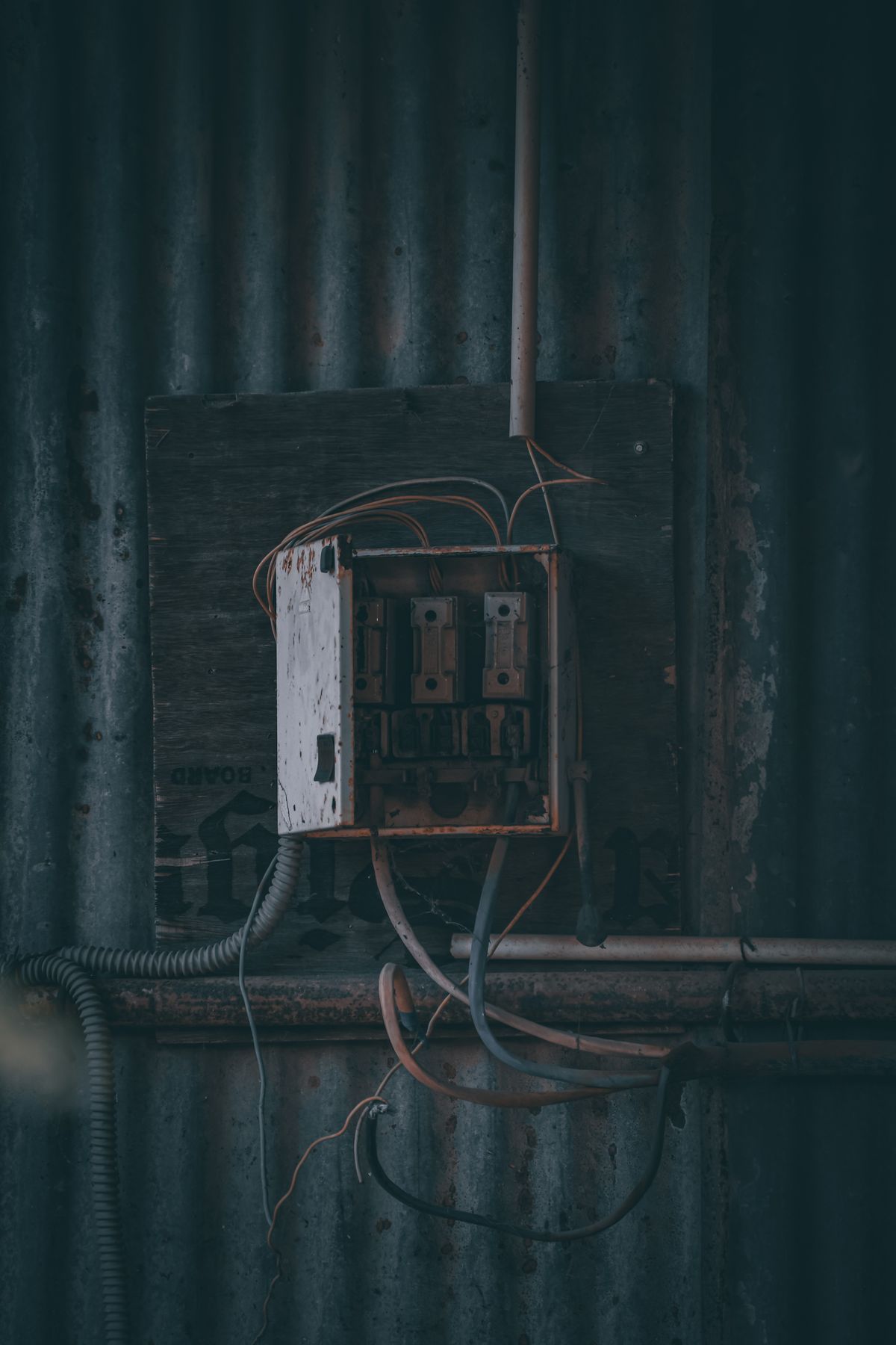 Quadro elétrico antigo e enferrujado, com fios expostos e emendas aparentes