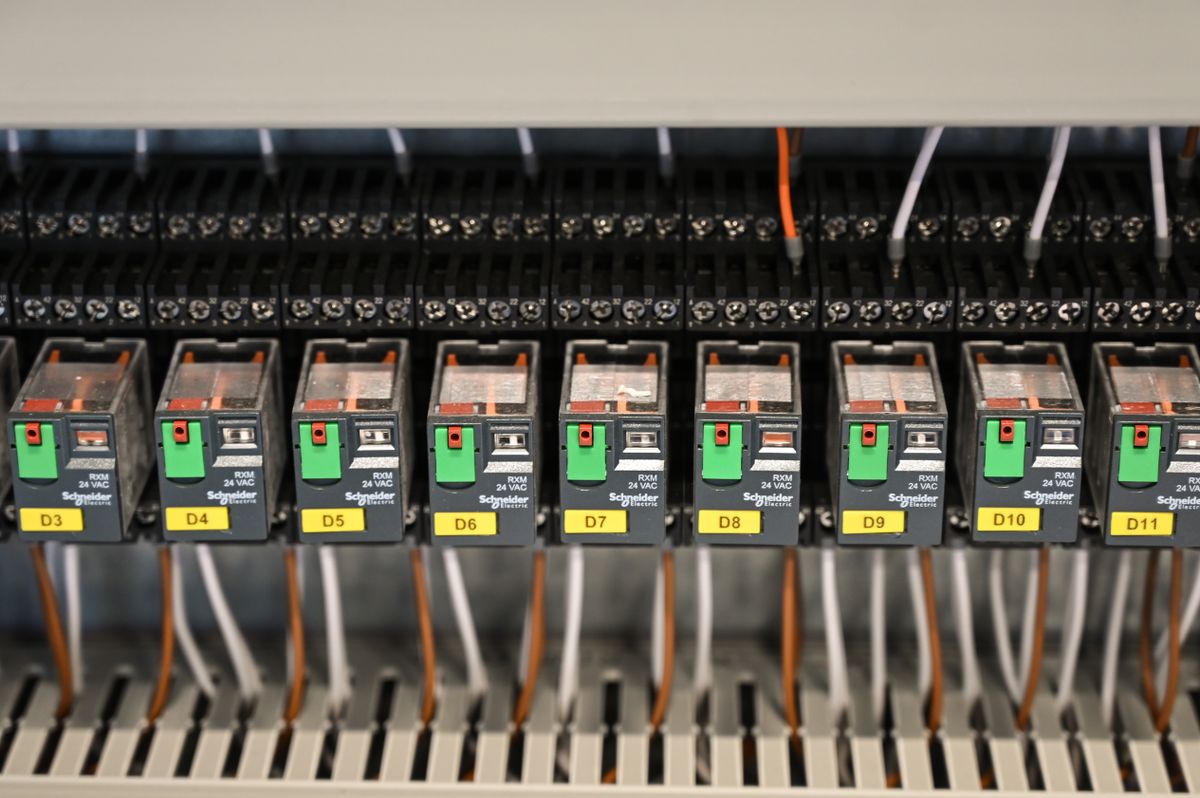 Relés de comando identificados um a um em trilho DIN, com canaleta de fiação em painel industrial